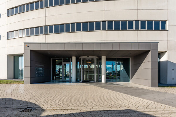 Vooraanzicht van de hoofdingang van het kantoorgebouw Rivium Quadrant 75 met een draaideur en moderne gevel.
